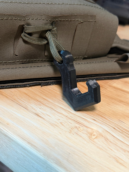Compound bow hanging by its D-loop from a wearable bow holder on a hunter's kit